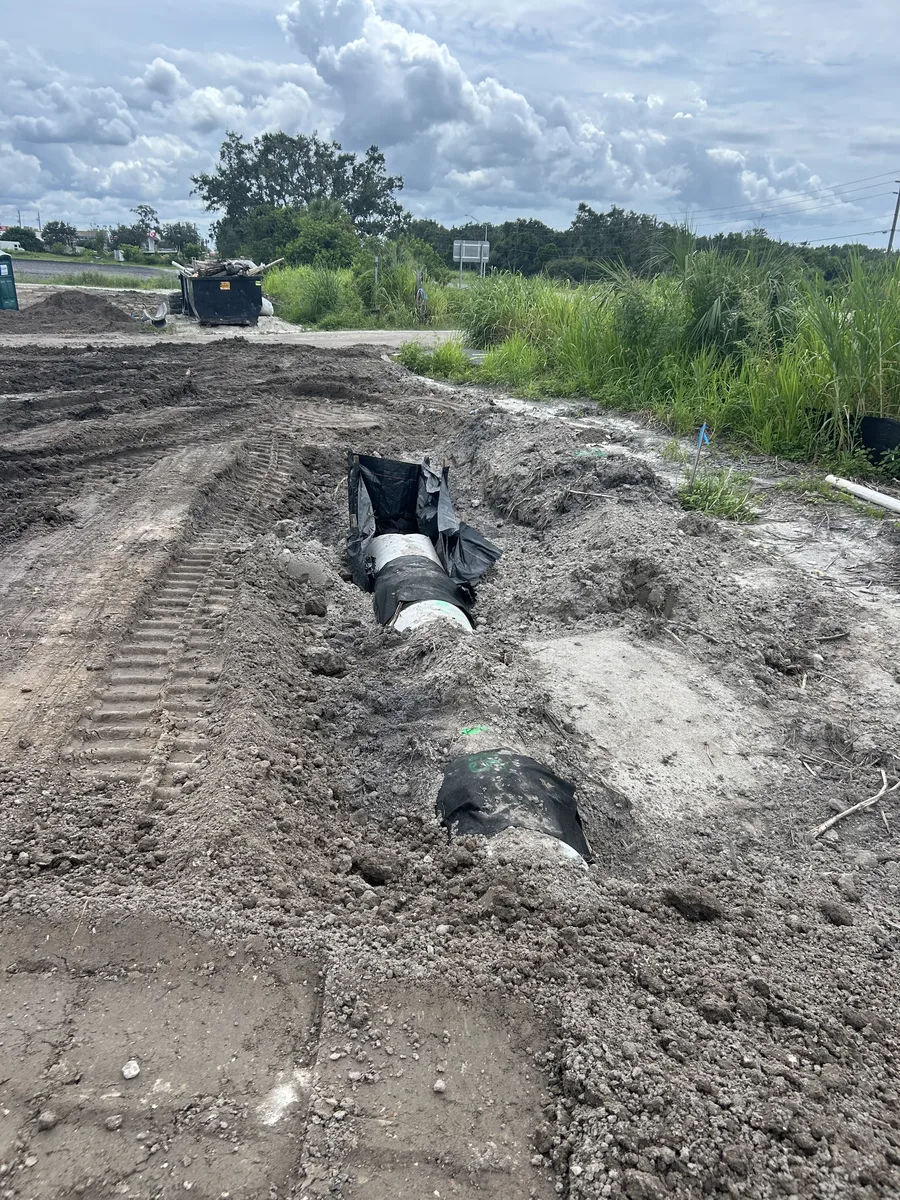 Crew installing large concrete drainage pipe with Yanmar excavator in Palmetto FL