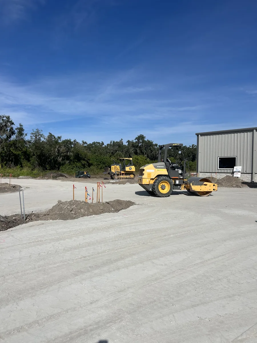 Volvo vibratory roller and Deere bulldozer grading commercial building site in Bradenton FL