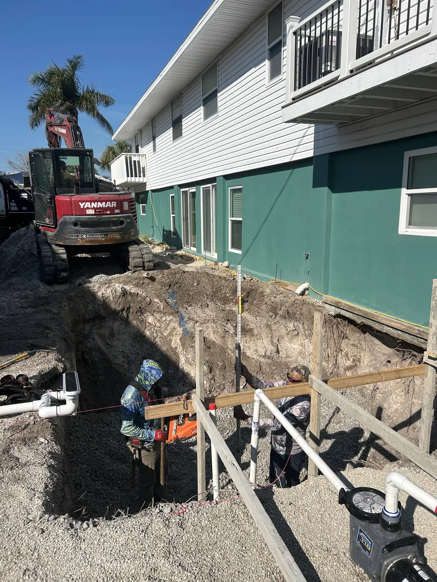 Yanmar excavator and crew performing pool excavation beside coastal building in Sarasota FL