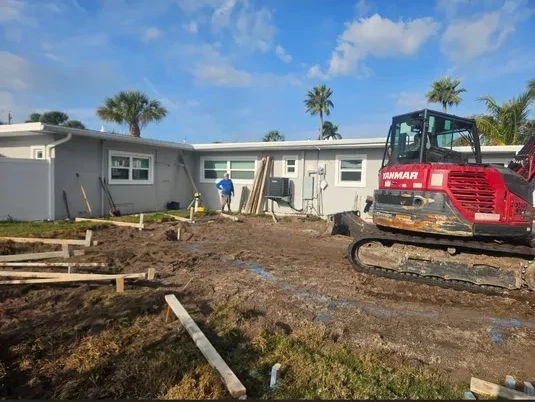 Red Yanmar mini excavator at residential foundation excavation site with worker in Bradenton FL