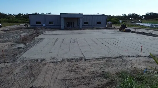 Volvo vibratory drum roller compacting commercial parking lot with grade stakes in Bradenton FL