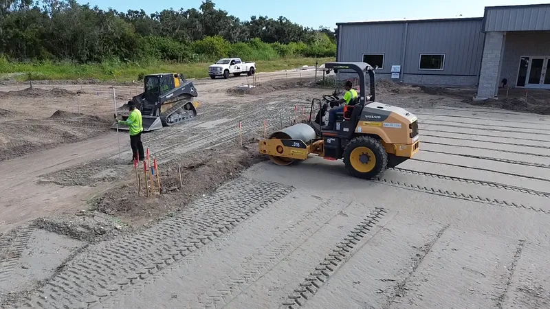 Volvo drum roller with skid steer and crew performing commercial site grading in Bradenton FL